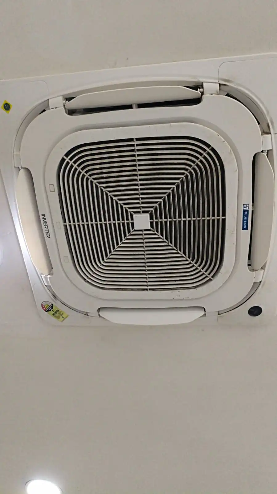Cassette AC unit being serviced in a commercial showroom ceiling
